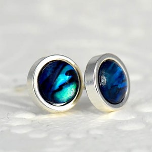 May include: A pair of silver stud earrings with blue abalone shell inlays.