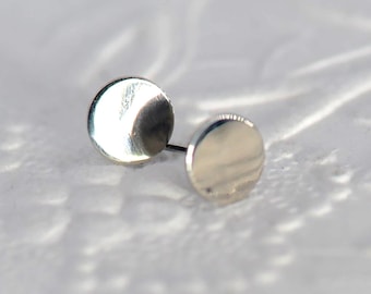 Op de afbeelding: Een paar zilveren oorbel studs met een rond ontwerp. De oorbellen zijn klein en eenvoudig, waardoor ze een veelzijdig accessoire zijn.