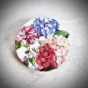 Peut inclure: Sous-verre rond avec un motif floral d'hortensias roses, rouges et bleus. Le sous-verre a un fond blanc et une illustration détaillée des fleurs. Un article décoratif pour la décoration intérieure.