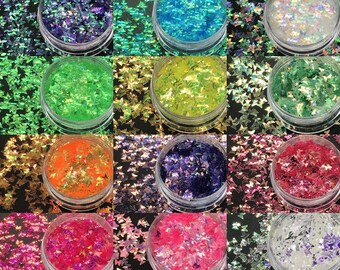 May include: A collection of small, clear plastic jars filled with butterfly-shaped glitter in various colors. The colors include shades of purple, blue, green, yellow, orange, and pink. The glitter is scattered around the jars.