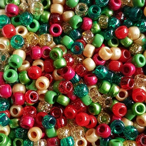 May include: A close-up of a collection of colourful beads. The beads are in shades of red, green, gold, and cream. The beads are cylindrical with a hole through the centre, suitable for stringing.