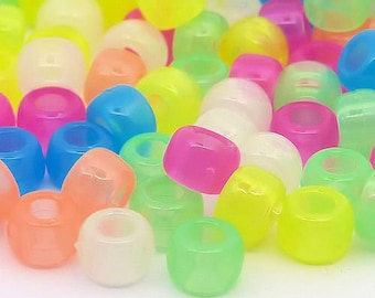 Puede incluir: Una colección de cuentas de pony translúcidas y coloridas en varios tonos de rosa, azul, verde, amarillo y naranja. Las cuentas son cilíndricas con un agujero grande en el centro, perfectas para manualidades y bisutería.