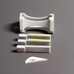 May include: A set of three gray 3D printed bridge supports with yellow accents. The supports are designed to be used with a model train set. The set also includes a white plastic arrow with the word "Blaze" written on it.