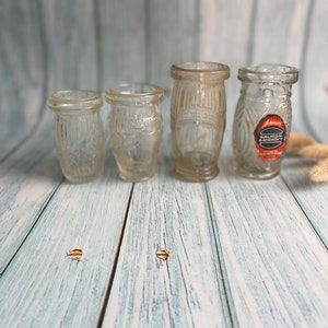 Op de afbeelding: Vier glazen potten met een transparante kleur en een getextureerd oppervlak. De kleinste pot staat links en de grootste rechts. De grootste pot heeft een etiket met de tekst "Armour's Salmon Anchovy".