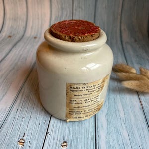 Puede incluir: Un tarro de cerámica blanco con tapa de corcho y una etiqueta que dice "MEAUX PREPARED MUSTARD Ingredients: Mustard seeds, Vinegar, Salt. Nearly Weight: 17 Oz. SENF. IN MEAUX ZUBE. Hetellung: Korn Senf. Essig. Salz. Annäherndes Gewicht 500 g. MOSTARDA DI MEAUX SPON. Ingredienti: Mostarda. Aceto. Sale. Peso Netto 500 Grammi."