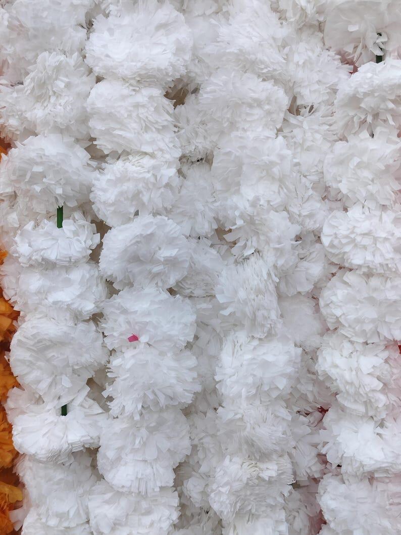 K&ouml;nnte beinhalten: Nahaufnahme einer Girlande aus wei&szlig;en Papierblumen. Die Blumen sind in einer Reihe angeordnet und alle gleich gro&szlig;. Die Girlande besteht aus vielen einzelnen Blumen, die miteinander verbunden sind.