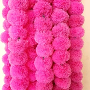K&ouml;nnte beinhalten: Eine Girlande aus rosa Papierblumen, jede Blume ist in Pomponform mit vielen Schichten gekr&auml;useltem Papier.