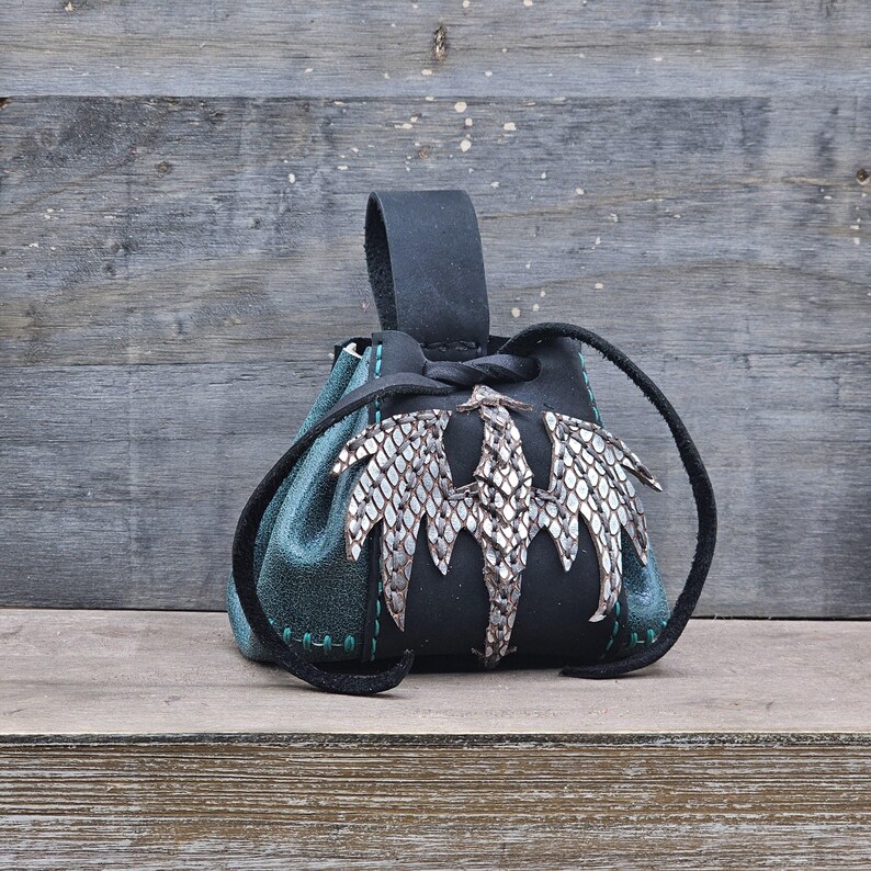 Small leather belt pouch with a silver scaled dragon hand sewn on the front. The main body is the color of your choice (green or red). The bag has a drawstring closure.