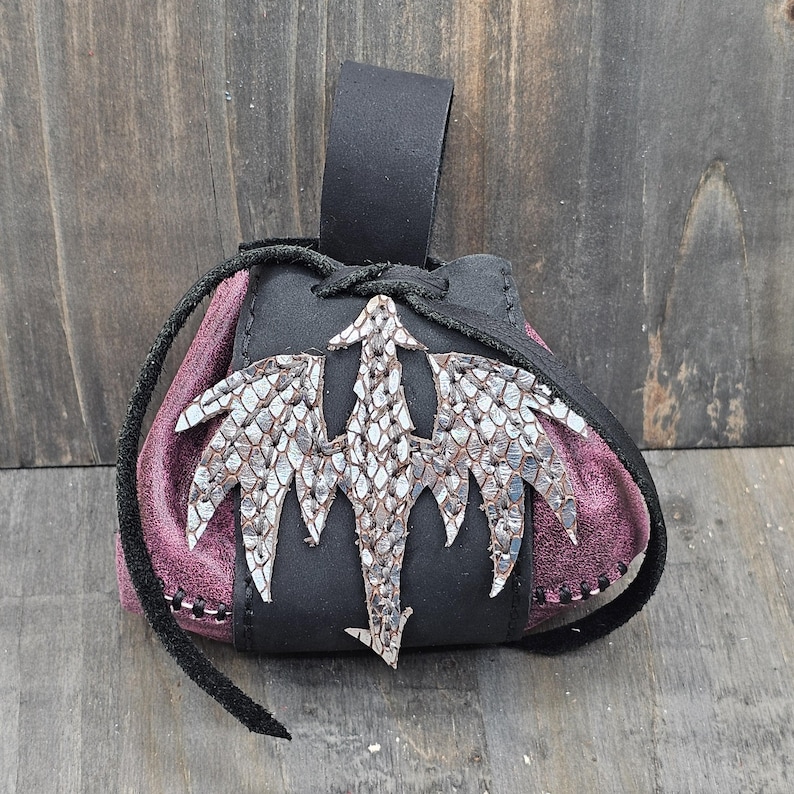 Small leather belt pouch with a silver scaled dragon hand sewn on the front. The main body is the color of your choice (green or red). The bag has a drawstring closure.