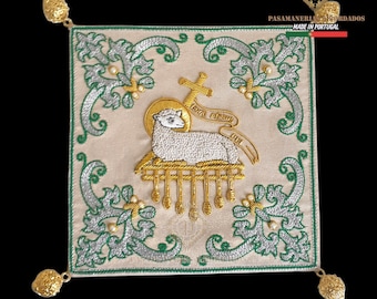 May include: Embroidered square textile with a central lamb motif, surrounded by green and silver floral designs. Gold accents and corner embellishments add detail. The text "PASAMANERIA BORDADOS MADE IN PORTUGAL" is visible.