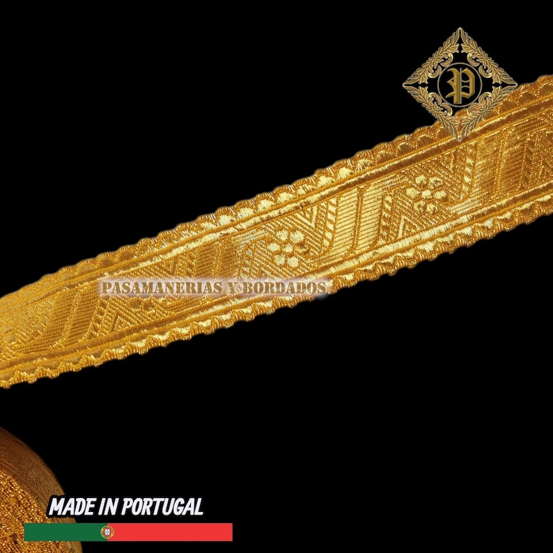 May include: Gold-colored decorative trim with intricate floral and geometric patterns. The trim has a textured surface and is labeled "PASAMANERIAS Y BORDADOS" and "MADE IN PORTUGAL". The trim is against a black background.