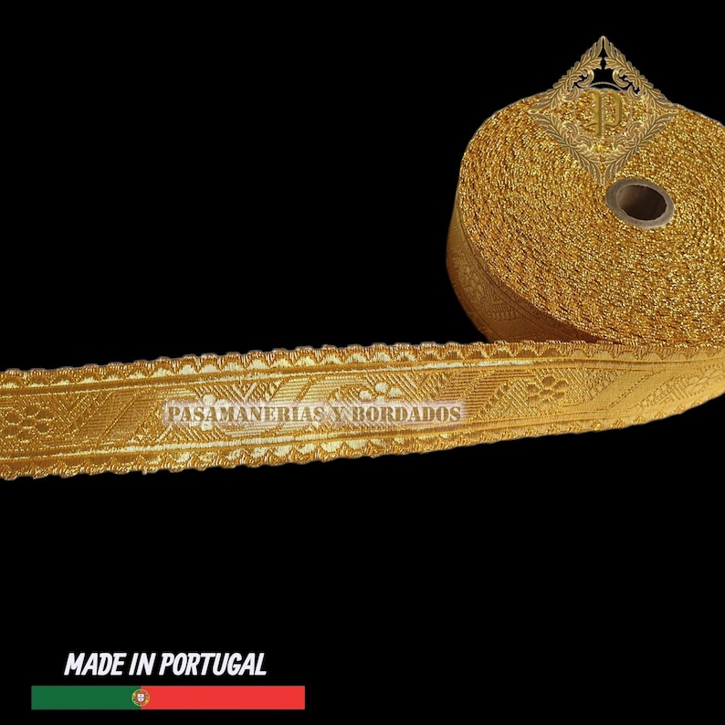 May include: A roll of gold-colored decorative trim with intricate floral and geometric patterns. The trim is labeled "PASAMANERIAS Y BORDADOS" and "MADE IN PORTUGAL". The trim is likely used for embellishing clothing or crafts.