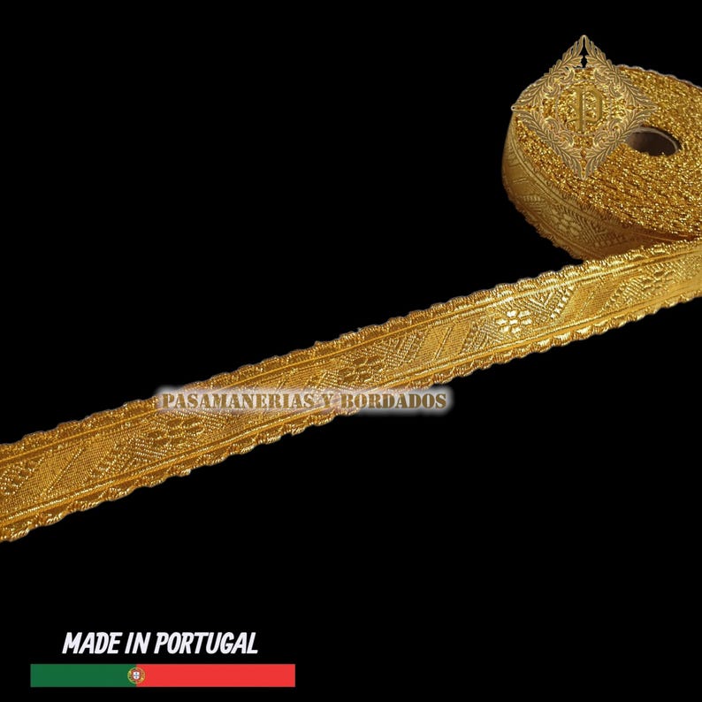 May include: A roll of gold-colored decorative trim with intricate woven patterns. The trim is labeled "PASAMANERIAS Y BORDADOS" and "MADE IN PORTUGAL". The trim has a scalloped edge and is likely used for embellishing clothing or crafts.