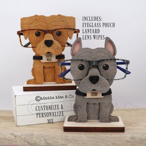 May include: Two wooden dog-shaped eyeglass holders. One is brown with tortoise shell glasses, the other is gray with gray-framed glasses. Each has a name tag. The text "CUSTOMIZE & PERSONALIZE ME" is visible.