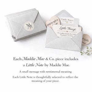 May include: A stack of light gray paper envelopes with a circular sticker featuring the initials "M" and "M". One envelope is open, revealing a card that reads "Little Things" and "Little Notes by Maddie Mae".