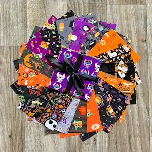 May include: A stack of 12 Halloween-themed fabric squares with various designs, including pumpkins, ghosts, and bats. The squares are tied together with a black ribbon and a purple and blue fabric square with a cartoon character in the centre.