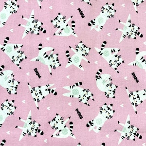 May include: A pink fabric with a repeating pattern of white and black cats doing yoga poses. The cats have black eyes and whiskers and are outlined in black. The background is a light pink with small white hearts.