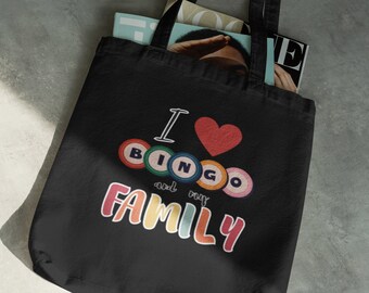 May include: Black tote bag with the phrase "I ❤️ BINGO and my FAMILY" in colorful text. The design includes a red heart and bingo balls. The bag is filled with magazines.