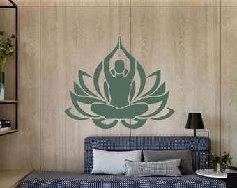 May include: A green silhouette of a person meditating in a lotus flower position on a wood wall. The person is sitting with their legs crossed and their hands raised in a prayer position. The lotus flower has seven petals.