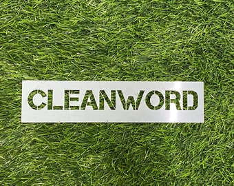 May include: A silver metal stencil, rectangular in shape, with the word "CLEANWORD" cut out. The stencil is placed on a bed of green artificial turf.
