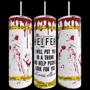 May include: A white tumbler with a red and yellow design. The tumbler has a black straw and the text "HEIFER I WILL PUT YOU IN A TRUNK AND HELP PEOPLE LOOK FOR YOU Don't mess with me!" printed on it.
