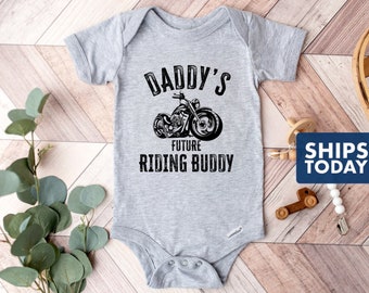 May include: Gray baby onesie with a black and white illustration of a motorcycle and the text "Daddy's Future Riding Buddy".