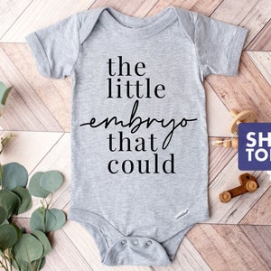 Peut inclure: Un body b&eacute;b&eacute; gris avec le texte "the little embryo that could" imprim&eacute; en noir.