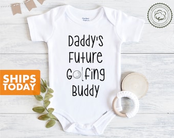 May include: White baby onesie with black text that reads "Daddy's Future Golfing Buddy" with a golf ball graphic.