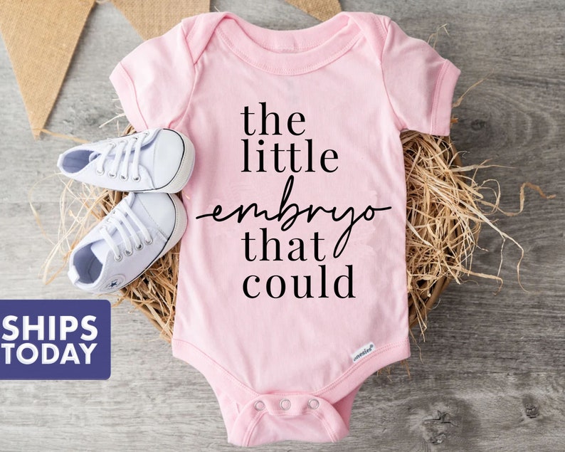 Peut inclure: Combinaison rose pour b&eacute;b&eacute; avec le texte "the little embryo that could" en noir.