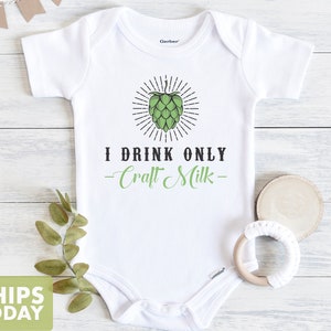 May include: White baby onesie with a green hop cone graphic and the text "I drink only -Craft Milk- "