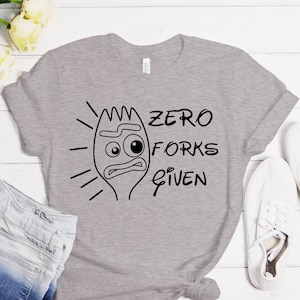 Puede incluir: Una camiseta gris con una imagen de dibujos animados negra de un tenedor con una cara y el texto "Zero Forks Given".