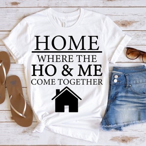May include: White t-shirt with black text that reads "HOME WHERE THE HO & ME COME TOGETHER" and a black silhouette of a house.
