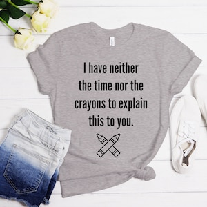 May include: Gray t-shirt with the text "I have neither the time nor the crayons to explain this to you." and a black and white illustration of two crossed crayons.
