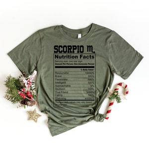 May include: Green t-shirt with a black graphic that reads "SCORPIO M. Nutrition Facts" and lists personality traits with percentages. The graphic is styled like a nutrition label.