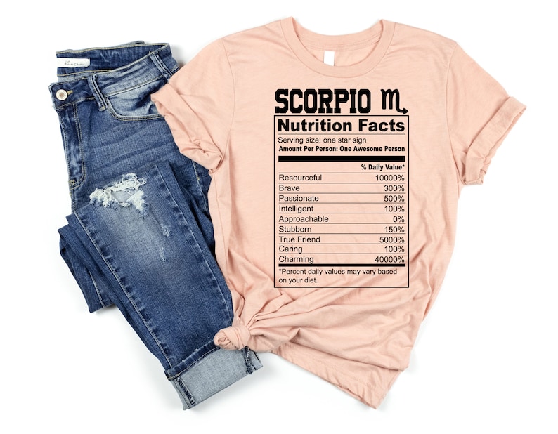 May include: A peach-colored t-shirt with the text "SCORPIO M. Nutrition Facts" and a table listing personality traits with percentages. The table includes traits like "Resourceful", "Brave", "Passionate", "Intelligent", "Approachable", "Stubborn", "True Friend", "Caring", and "Charming".