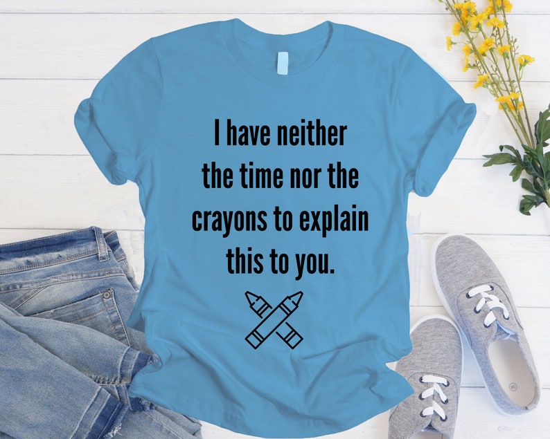 May include: A light blue t-shirt with the text "I have neither the time nor the crayons to explain this to you." and a black and white illustration of two crossed crayons.