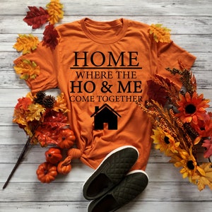 May include: Orange t-shirt with black text that reads "Home where the ho & me come together" and a black house icon.
