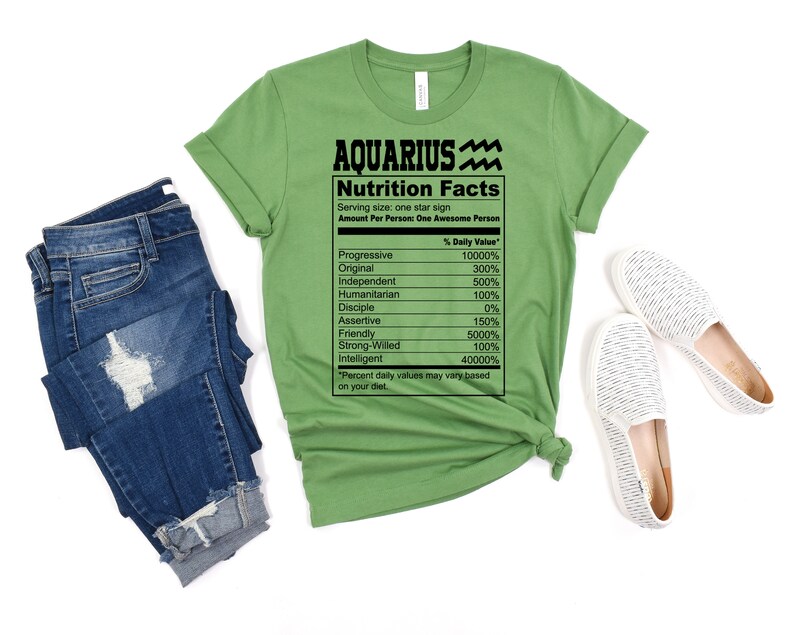 May include: Green t-shirt with a black graphic of a nutrition facts label for Aquarius. The label lists traits like progressive, original, independent, humanitarian, disciple, assertive, friendly, strong-willed, and intelligent with a percentage daily value for each.
