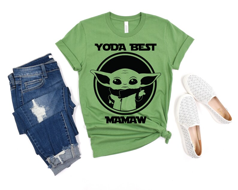 May include: Green t-shirt with a black and white graphic of a baby Yoda character. The text "Yoda Best Mamaw" is printed on the shirt.