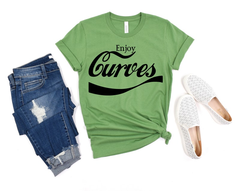 May include: A green t-shirt with the text "Enjoy Curves" in a black, stylized font that resembles a popular soda brand logo.