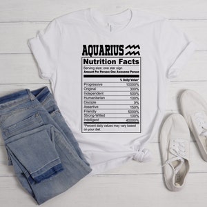 May include: White t-shirt with a black graphic of a nutrition facts label for Aquarius. The label lists traits like "Progressive", "Original", "Independent", and "Strong-Willed" with percentages next to each trait.