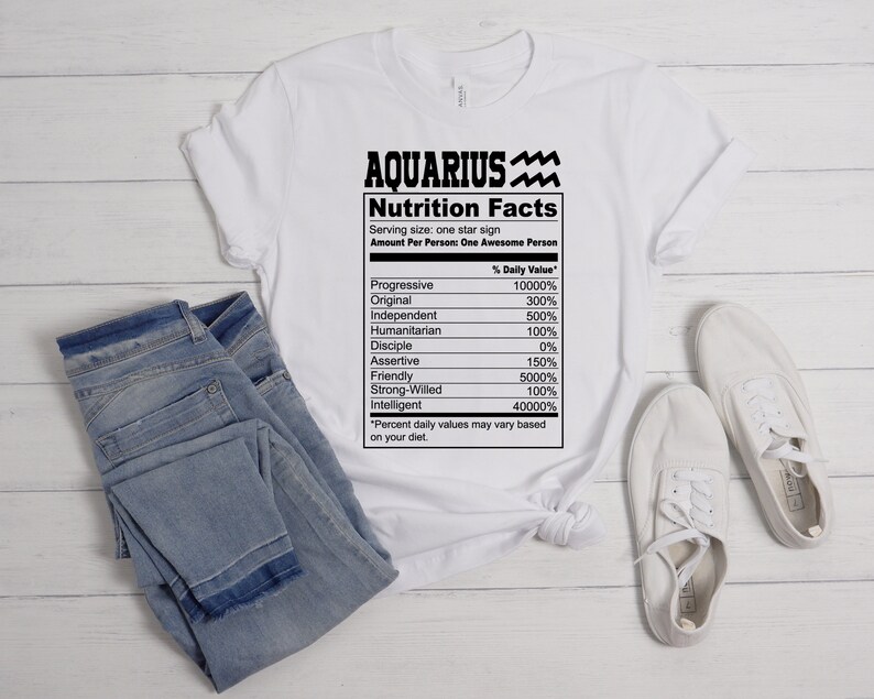 May include: White t-shirt with a black graphic of a nutrition facts label for Aquarius. The label lists traits like "Progressive", "Original", "Independent", and "Strong-Willed" with percentages next to each trait.