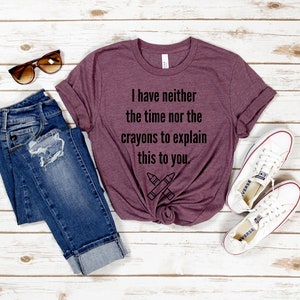 May include: A maroon t-shirt with the text "I have neither the time nor the crayons to explain this to you." and a drawing of two crossed crayons.
