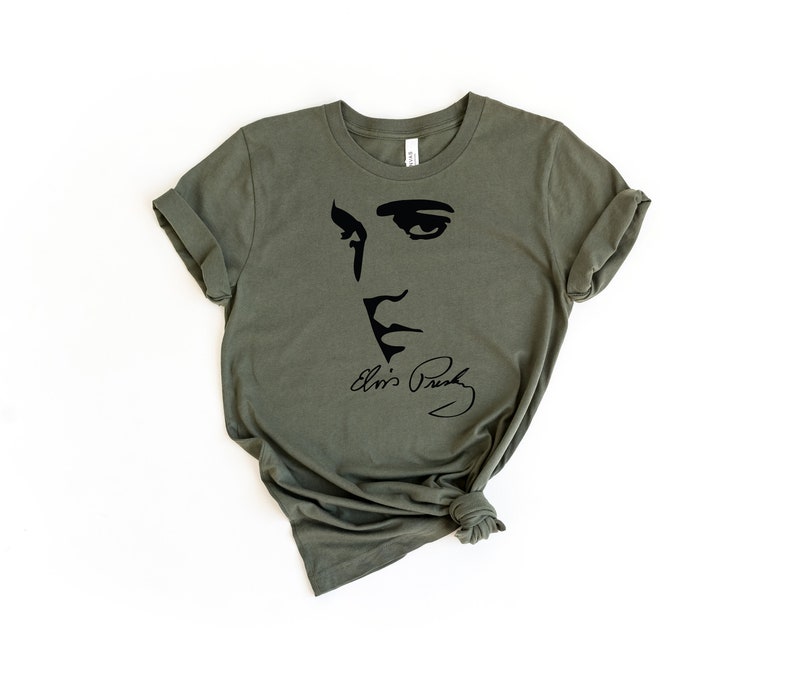 May include: A green t-shirt with a black silhouette of Elvis Presley's face and his signature.