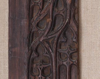 May include: A weathered, dark brown wooden panel with intricate carved Gothic-style tracery. The design features arched windows and ornate, flowing patterns, showcasing a rich, aged texture.