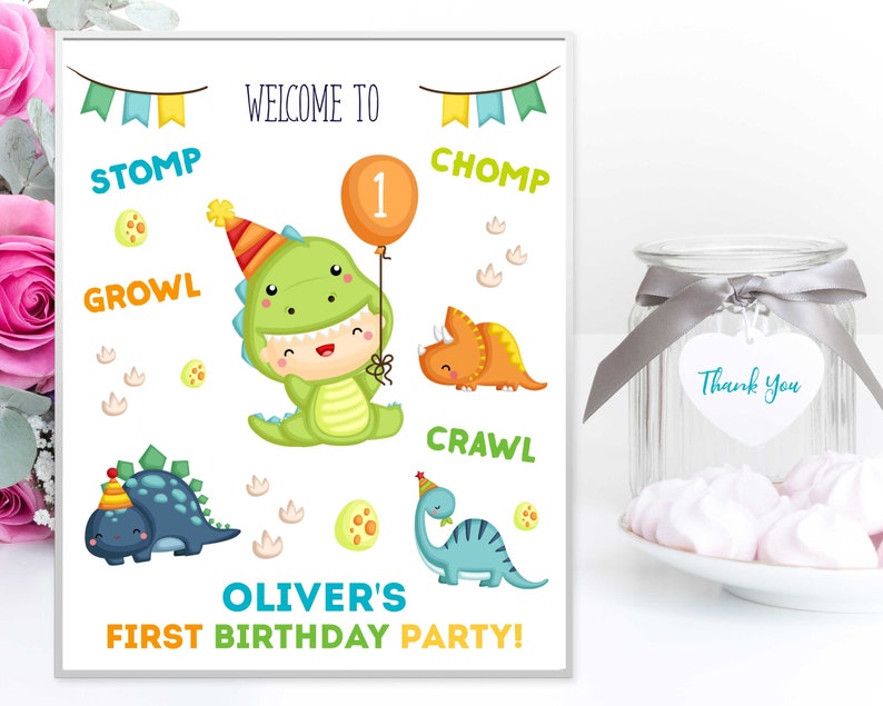 May include: A printable sign for a dinosaur-themed first birthday party. The sign features a green dinosaur wearing a party hat and holding a balloon with the number 1 on it. The sign also includes the words "Welcome to", "Stomp", "Growl", "Chomp", "Crawl", "Oliver's First Birthday Party!"