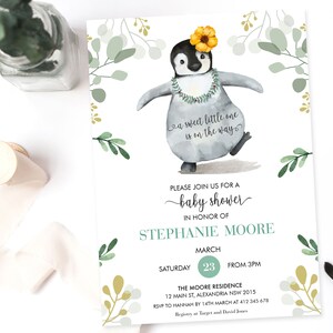 May include: A baby shower invitation with a watercolor illustration of a penguin wearing a flower crown and a lei. The invitation is decorated with green and gold floral accents. The text on the invitation reads "a sweet little one is on the way" and "Please join us for a baby shower in honor of Stephanie Moore. Saturday, March 23 from 3pm. The Moore Residence, 12 Main St, Alexandria NSW 2015. RSVP to Hannah by 14th March at 412 345 678. Registry at Target and David Jones."