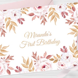 Pu&ograve; includere: Un biglietto bianco con un bordo floreale dorato e il testo "Miranda's First Birthday" in lettere dorate scintillanti.