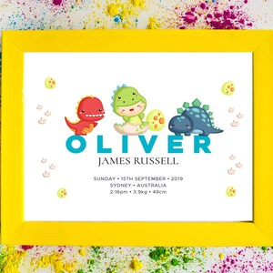 May include: A yellow frame with a white background featuring a dinosaur-themed baby announcement for Oliver James Russell. The announcement includes the date, time, weight, and length of the baby. The dinosaurs are green, blue, and red.