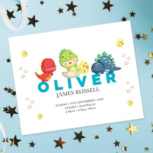 May include: A white card with a blue dinosaur theme announcing the birth of Oliver James Russell. The card includes the date and time of birth, weight, and length. The card features three cartoon dinosaurs, one red, one green, and one blue.
